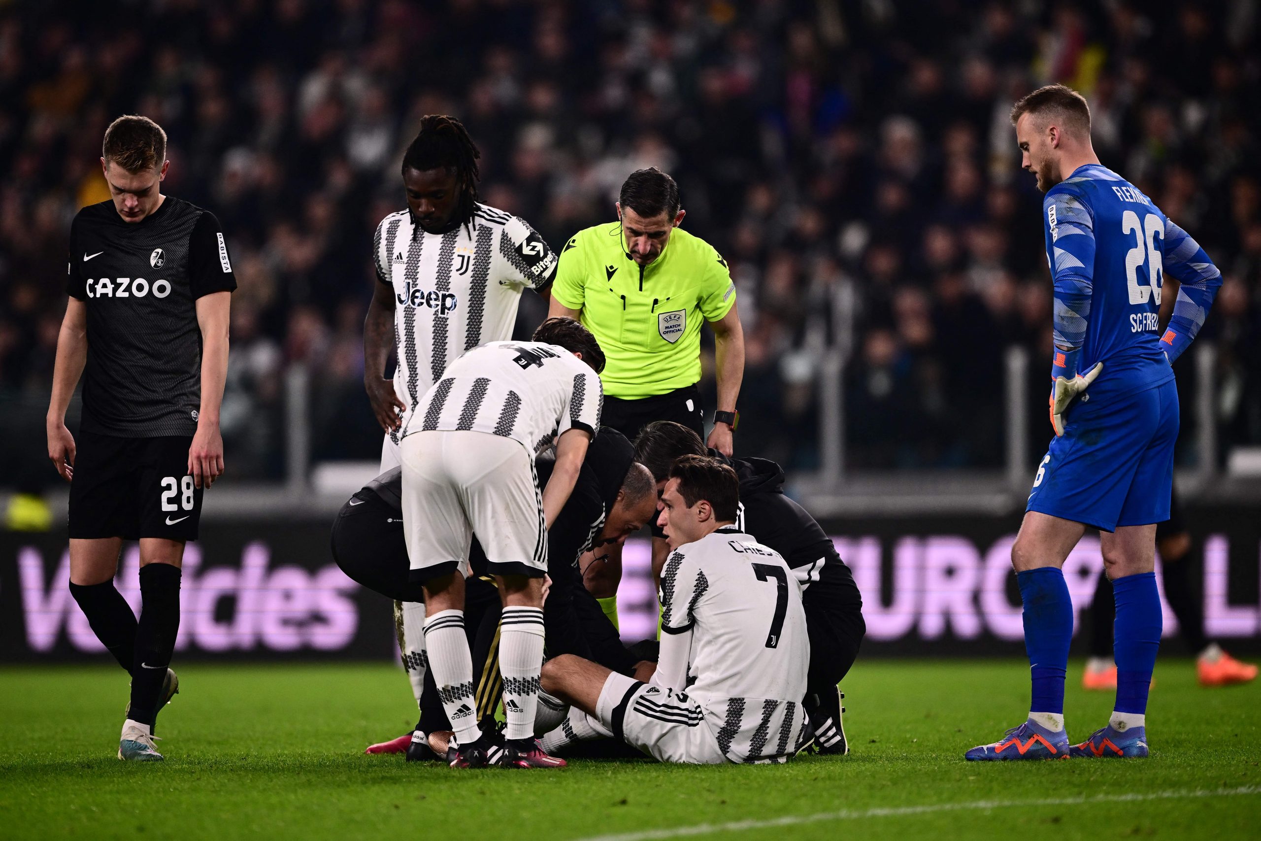Greek referee Tasos Sidiropoulos, SC Freiburg's German defender Matthias Ginter (L), Juventus' Italian forward Moise Kean (2ndL) and SC Freiburg's Dutch goalkeeper Mark Flekken (R) stand by as medics tend to Juventus' Italian forward Federico Chiesa (Bottom) during the UEFA Europa League round of 16 first leg football match between Juventus and SC Freiburg on March 9, 2023 at the Juventus stadium in Turin. (Photo by Marco BERTORELLO / AFP) (Photo by MARCO BERTORELLO/AFP via Getty Images)